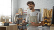 © Krakenimages.com - Young hispanic man with a beard working in a bakery shop, holding utensils with bread and pastries on shelves in the background