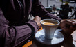© almudena - Hands of a man holding the metal spoon of his delicious coffee to drink it on the terrace of a cafeteria on a sunny morning.