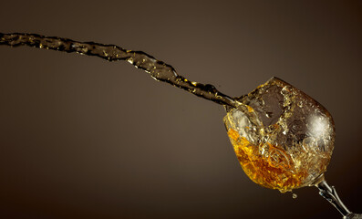 Wall Mural - Glass and brandy splash on a brown background.