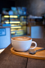 Wall Mural - Hot coffee latte with latte art milk foam in cup mug on wood desk on top view. As breakfast In a coffee shop at the cafe,during business work concept,vintage style