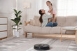 © New Africa - Mother spending time with her daughter in room, focus on robotic vacuum cleaner