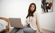 © RooftopStudioBangkok - business woman sitting with laptop in modern room, exuding confidence and professionalism. She wears stylish outfit, perfect for work from home setting