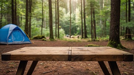 Wall Mural - A empty wooden table in the foreground with a tent and trees in the blurred background, suggesting an outdoor camping scene in a forest
