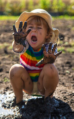 Poster - Child playing in mud. Selective focus.