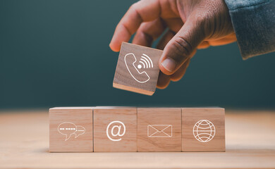 Poster - Contact us concept. Tecnology for communication with customers support contact. Businessman holding wooden cube with symbol of telephone, email, chat, Website page contact and www. Marketing.