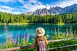 © unai - Tourist enjoying the breathtaking view of lake carezza and the dolomites in summer