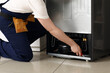 © Pixel-Shot - Male worker repairing refrigerator in kitchen, closeup