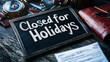 © Maksym - A rustic blackboard with the words 'Closed for Holidays' in artistic chalk lettering, resting on a table alongside a travel journal, compass, and boarding pass