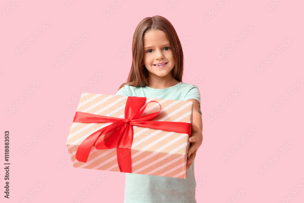 Happy little girl with gift box on pink background