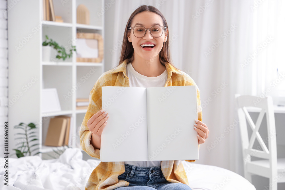 Young woman with blank magazine in bedroom