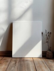 Poster - blank canvas mockup leaning against white wall on wooden floor with soft light and gentle shadows for art presentation and decoration