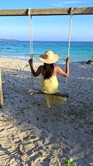 Wall Mural - Relax on Koh Munnork Island as the golden sun sets over the horizon. Enjoy a tranquil swing by the beach, surrounded by soft waves and warm sands, An Asian women on a swing at the beach