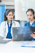 © NanSan - Two young female doctors sit at a table, discussing a patient's blood vessel sample. They collaborate over medical charts, focusing on diagnosis and treatment strategies with professional precision