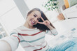 © deagreez - Cheerful young woman posing indoors making peace sign in bright daylight n cozy living room natural daylight