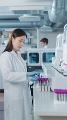 Aufkleber - Vertical Screen: Biochemists Collaborating in a Laboratory. Asian Female Researcher Loading Test Tubes with Blood Samples Into a Centrifuge while Her Coworker Reviews Experimental Data on a Computer