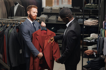 Wall Mural - Consultant helps African American man decide on choice of suit. Concept business clothes store for male