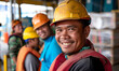 © Hana-AI  - Smiling Construction Worker in Safety Gear,Close-up of a cheerful construction worker in a hard hat and safety vest, with colleagues in the background at a worksite.