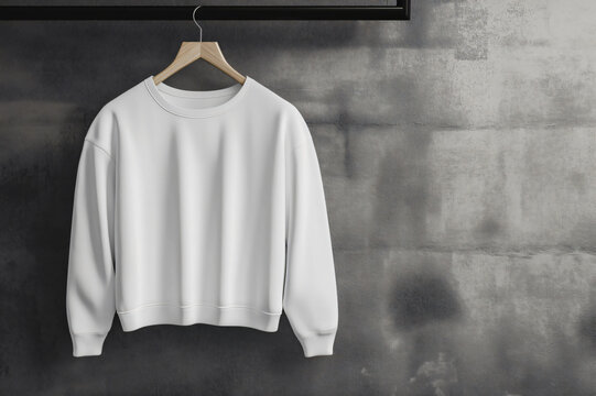 Customizable white crewneck sweatshirt mockup displayed on a hanger in a minimalist setting with a concrete wall, perfect for showcasing apparel designs. ,