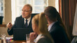 © master1305 - Senior businessman shares ideas and insights with colleagues during formal meeting, fostering teamwork and collaboration. Concept of business, leadership communication, vision, corporate meeting