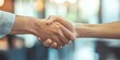© Pech - A close-up of hands of business partners shaking hands, symbolizing a successful partnership agreement, with a blurred office background.