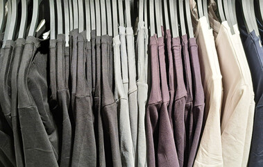 Row of shirts hanging on hangers in a clothing store. Fashion retail background. Display of casual t-shirts in a boutique. Shopping for apparel. Textile and fabric wardrobe selection.