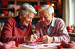 © Slepitssskaya - Two seniors smile and create heart decorations together in a warmly lit home filled with Valentine’s Day decorations