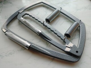 Poster - A metal trainer for the development of hand grip is lying on the table.