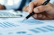 © Imagine World - Detailed Analysis of Financial Reports with Graphs and Data Tables Highlighted by a Business Professional's Hand Holding a Pen