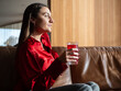 © 1 MEDIA - Woman sitting on couch, drinking a red beverage in elegant setting