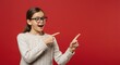 © StyleMuse - Excited young girl with glasses pointing sideways against red background