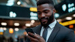 © Martn - A young, confident businessman in a suit is standing at an airport terminal. He's using his phone to book a taxi and order a hotel room. He's clearly on a business trip, traveling internationally.