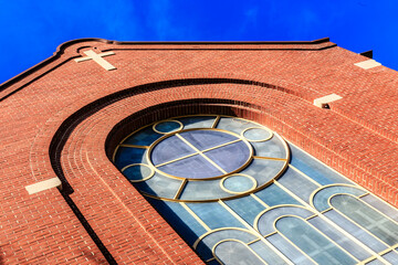 Wall Mural - A brick building with a large window and a cross on the roof