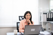© Fahng - Happy and successful businesswoman  inside office at workplace, worker smiling typing and looking at laptop Asian businesswoman is satisfied with results of achievements at work.