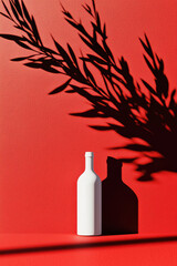 Poster - Minimalistic White Bottle with Leaf Shadow on Vibrant Red Background