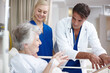 © peopleimages.com - Doctor, team and senior patient in hospital bed for healthcare results, surgery information or checkup notes. Elderly woman, nurse and talking with clipboard in clinic for health support or treatment