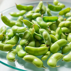 Vibrant, freshly picked green edamame beans, with slight sheen, scattered randomly on a transparent glass-like background, with individual beans showcasing varying degrees of slight unripe yellowish t