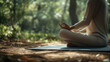 © Inna - Person meditating in a cross-legged position on a yoga mat in a serene forest setting