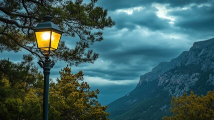 Poster - Street lamp illuminating mountain landscape under cloudy sky with pine trees in serene natural setting