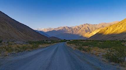 Poster - Mountain Road at Golden Hour Under Clear Blue Sky with Vibrant Landscape and Majestic Peaks in the Background