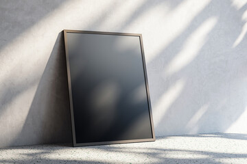 Aufkleber - Blank black frame leaning against a light concrete wall, on a speckled floor, in soft sunlight with shadows. 3D Rendering