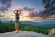 © bilanol - Sportive woman walking alone on hillside trail. Female hiker enjoying view of evening nature from rocky cliff on wilderness path. Active lifestyle concept