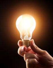 Poster - A hand holding a glowing light bulb in darkness
