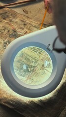 Wall Mural - Scientists work with cultural heritage of extinct human civilization. Senior archaeologist looks through magnifying lamp and examines ancient Egyptian papyrus with colleague in archaeological lab.