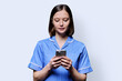 © Valerii Honcharuk - Young female nurse using smartphone, looking at phone on white background