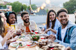 © Xavier Lorenzo - Happy diverse group of friends enjoying dinner barbecue and drinking wine in summer at home terrace