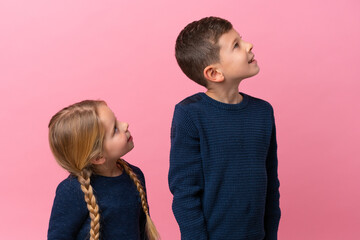 Wall Mural - Little caucasian brothers isolated on pink background looking up while smiling