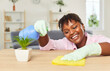 © Studio Romantic - Smiling african american maid polishing table with yellow cloth, close-up. Woman in gloves dusting furniture. Concept cleaning room, housekeeping, daily housework, cleaners work