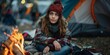 © Oksana - Young woman in a cozy outfit sits by a campfire near a tent. Concept of outdoor camping and relaxation. For use in camping or travel-themed content.