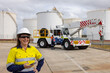 © Austockphoto - Happy woman in reflective clothing holding her mobile phone in the worksite.