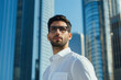 © The Stock Photo Girl - A confident man in a white shirt stands against a backdrop of modern skyscrapers.
